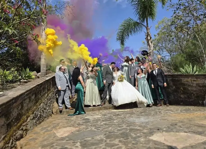 Novios e invitados celebrando con humo de colores